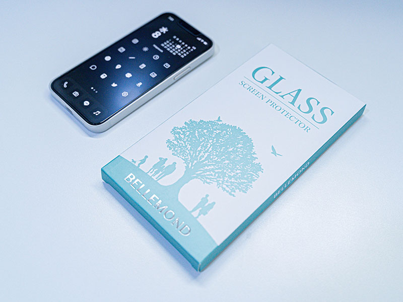 ベルモンド iPhone 13 mini 用 ガラスフィルムのパッケージとiPhoneを並べた画像